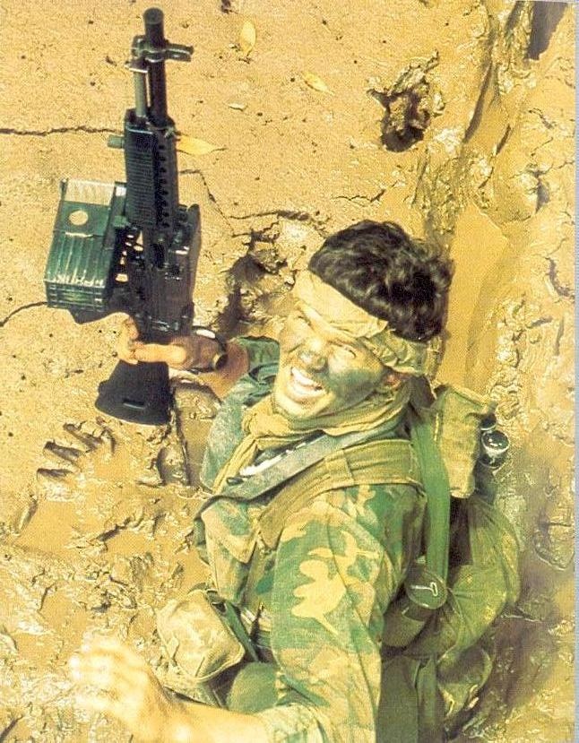 [SEALs] A Navy SEAL, carrying a Mk23 5.56mm Machine Gun (Stoner 63), moves through deep mud as he makes his way ashore from a boat, during a combat operation in South Vietnam in 1970. (U.S. Navy photograph by PHC A. Hill)